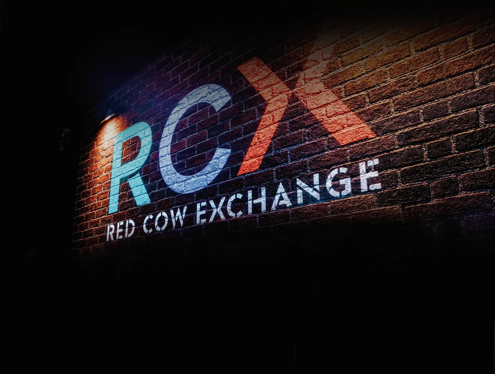 RCX — Red Cow Exchange logo projected on a brick wall